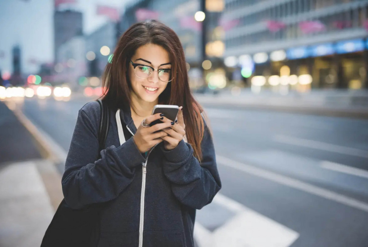 Junge Frau mit Brille schaut auf ihr Handy