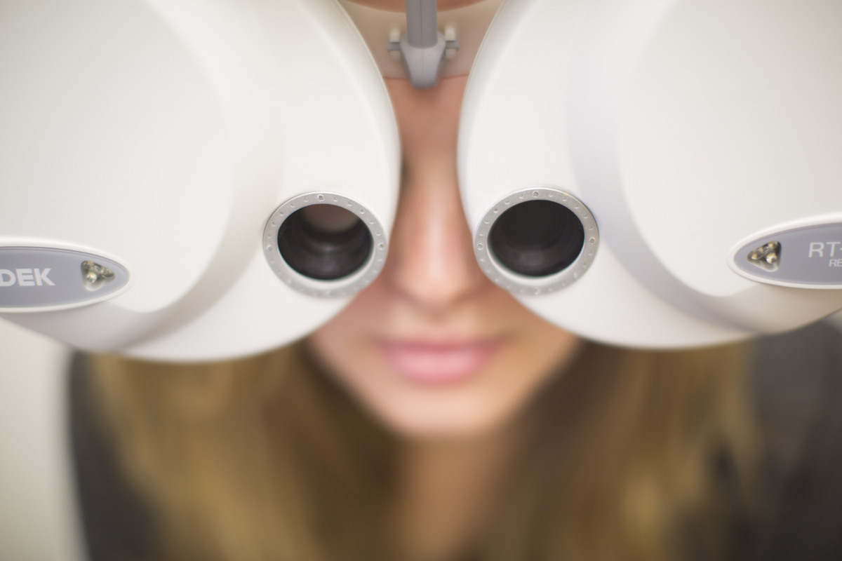Frau schaut bei Augenprüfung durch Augenmessgerät